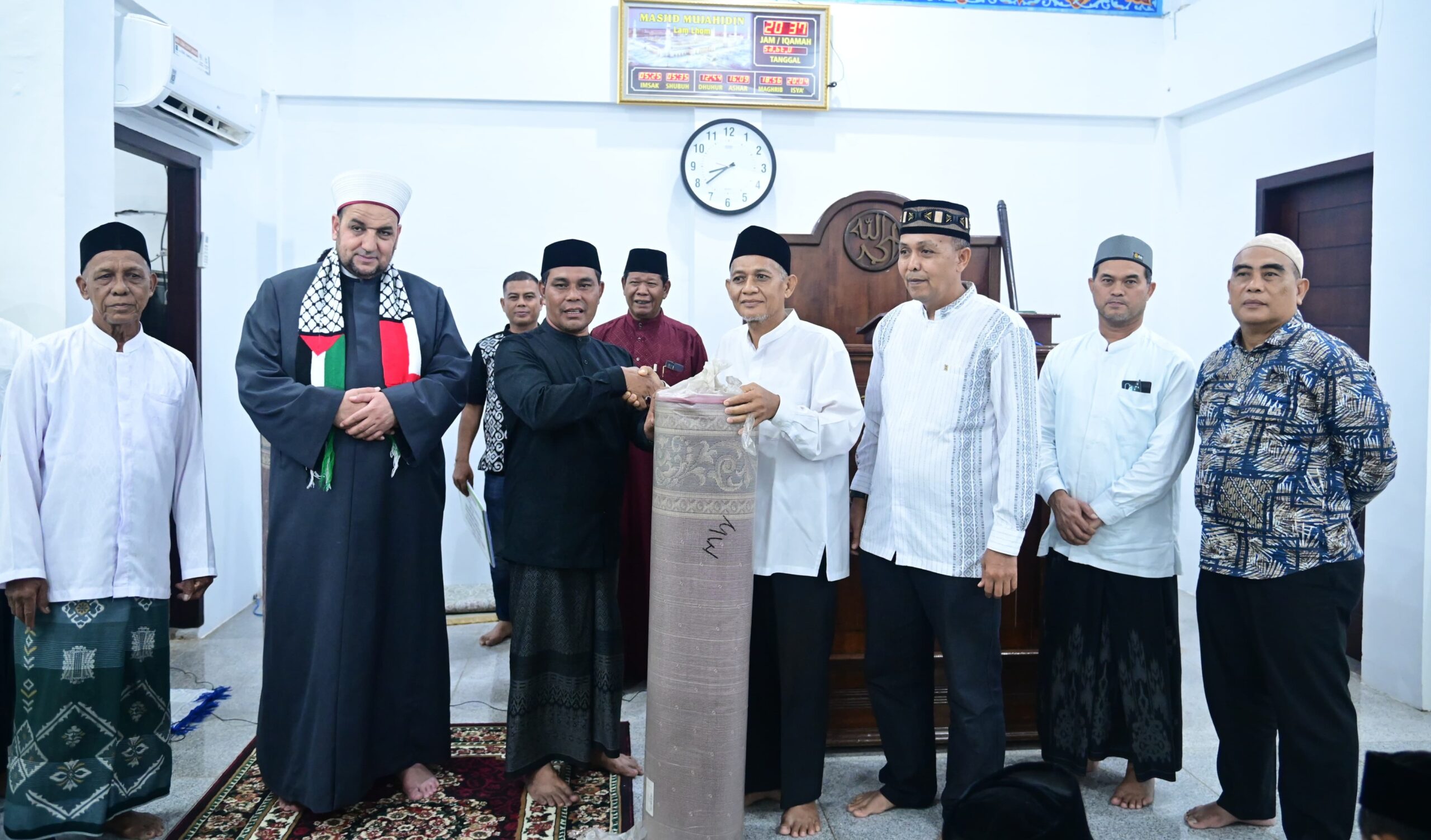 Bupati Aceh Besar H Muharram Idris yang akrab disapa Syech Muharram menyerahkan bantuan ambal sajadah kepada Tgk Salahuddin selaku Imuem Chiek Masjid Mujahidin Lamlhom dalam Safari Ramadhan tahun 1446 H di Masjid Mujahidin Kemukiman Lamlhom Kecamatan Lhoknga Kabupaten Aceh Besar Sabtu 832025 malam FOTO MC ACEH BESAR